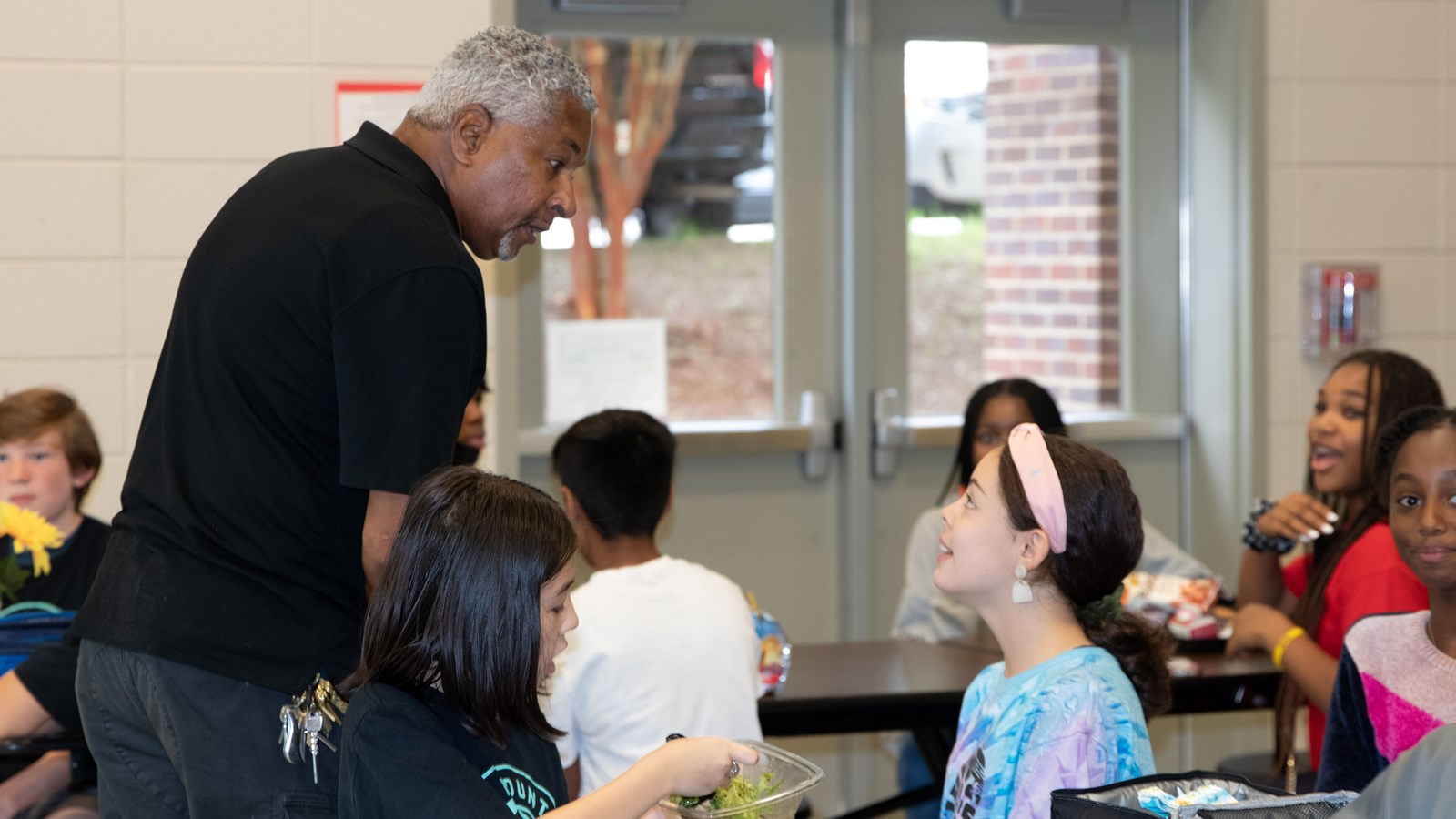 Pine Mountain Middle School custodian Mark Johnson chats with students at lunch.